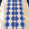 Blue and white crocheted lace table runner with circular medallions and diamond appliques displayed on dining table