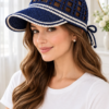 Navy blue crocheted lace visor cap with white stripes and bow ties worn by woman with long brown hair